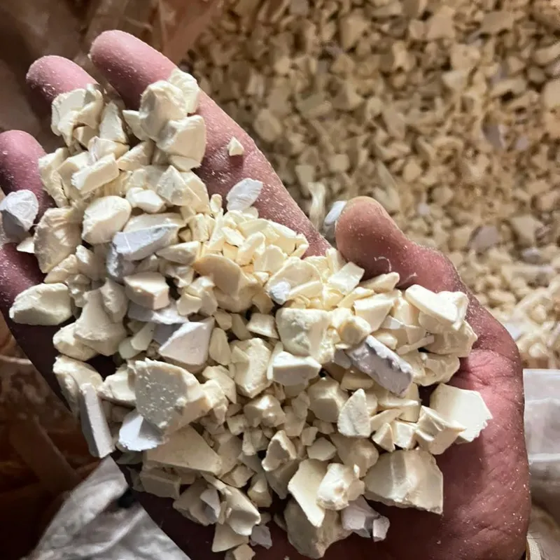 Hand holding off-white PVC pipe regrind