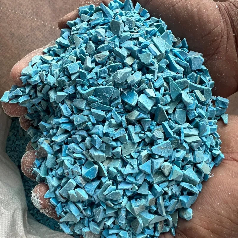 Blue PVC pipe regrind held in a hand, second view