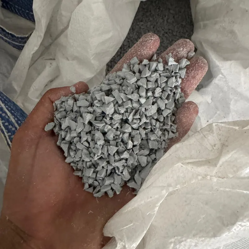 Handful of light grey PVC moulding regrind, closer view