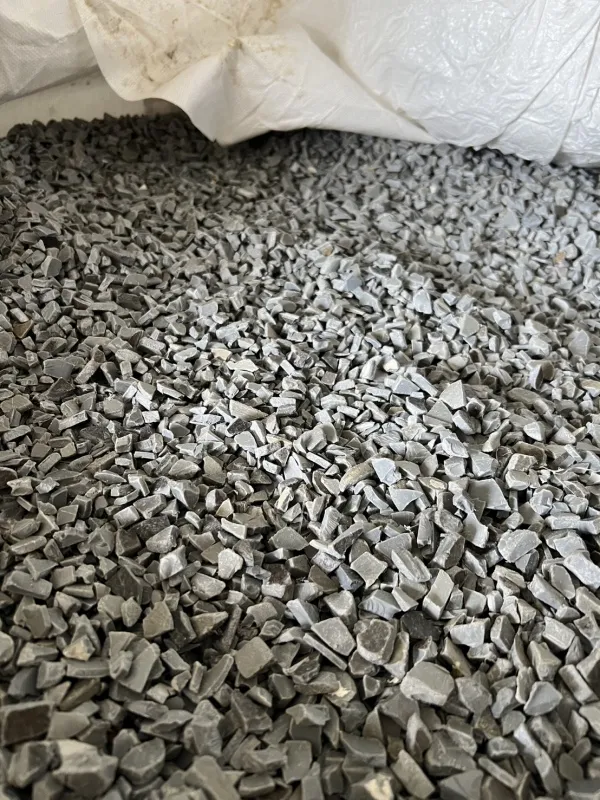 Grey PVC pipe regrind in an open bulk bag