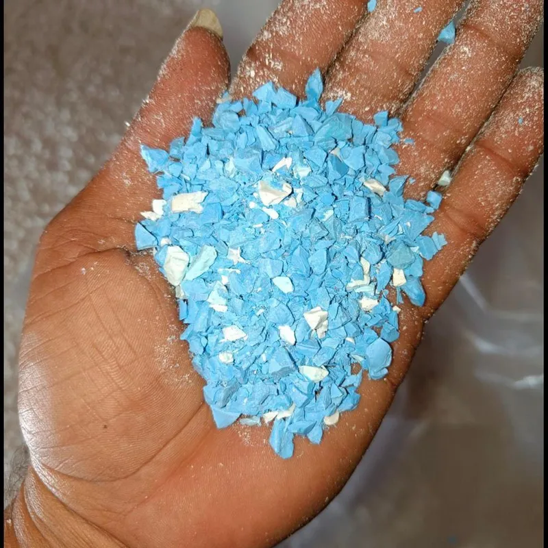 Blue and white PVC pipe regrind in an open hand