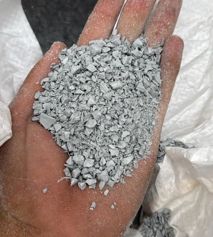 Light grey PVC moulding regrind in an open hand above the bag